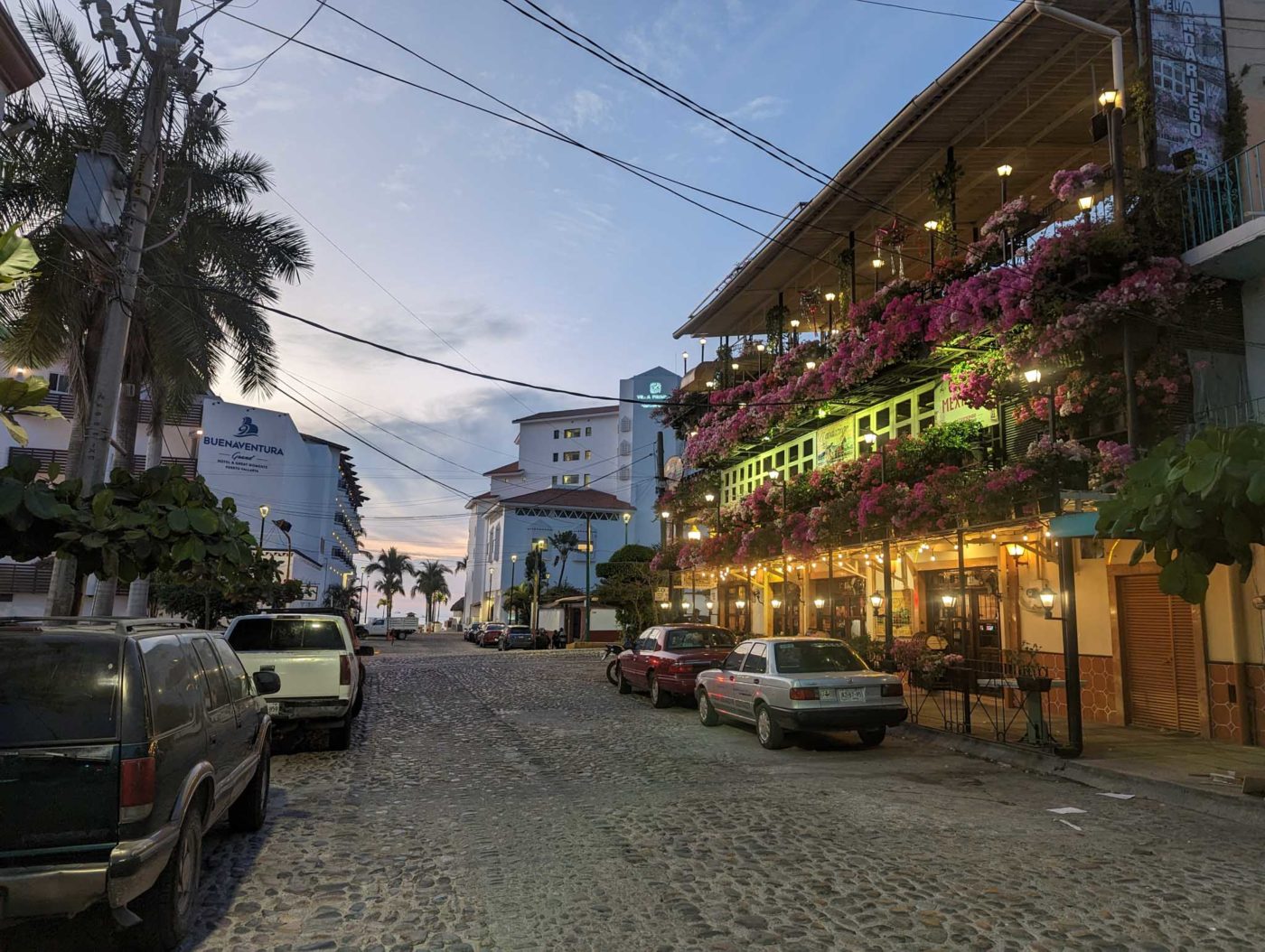 a street lined with parked cars next to tall buildings.