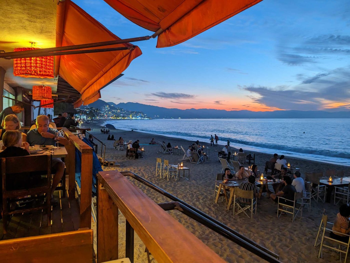 a group of people sitting at tables on a beach.