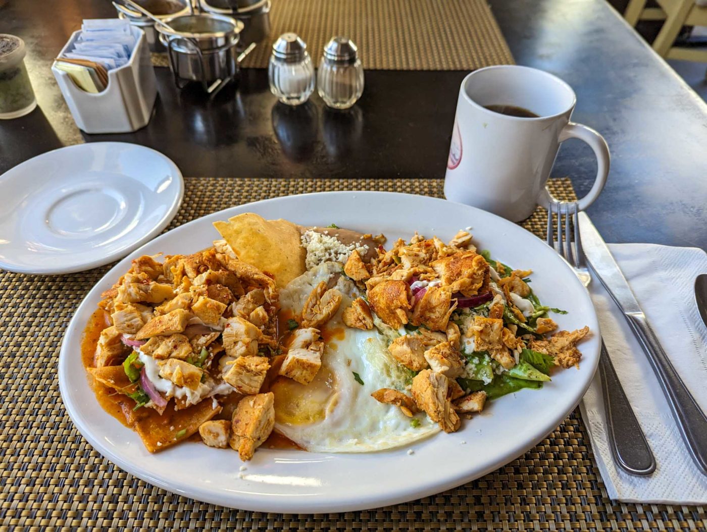 a white plate topped with food next to a cup of coffee.