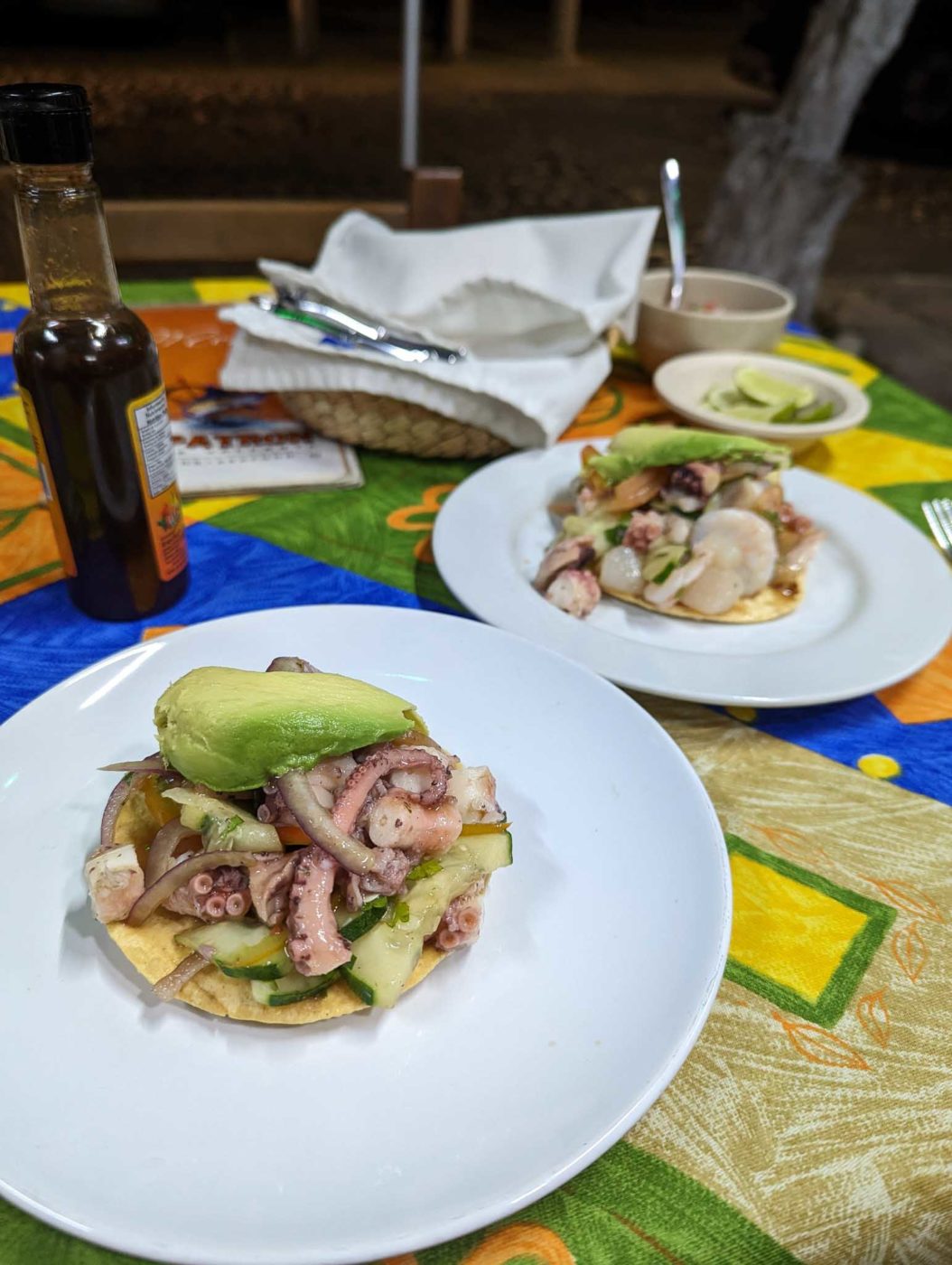 two plates of food on a table with a bottle of beer.