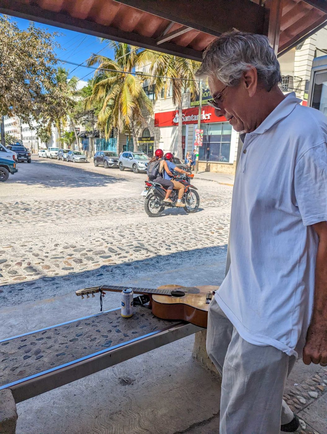 a man standing next to a bench with a guitar on it.