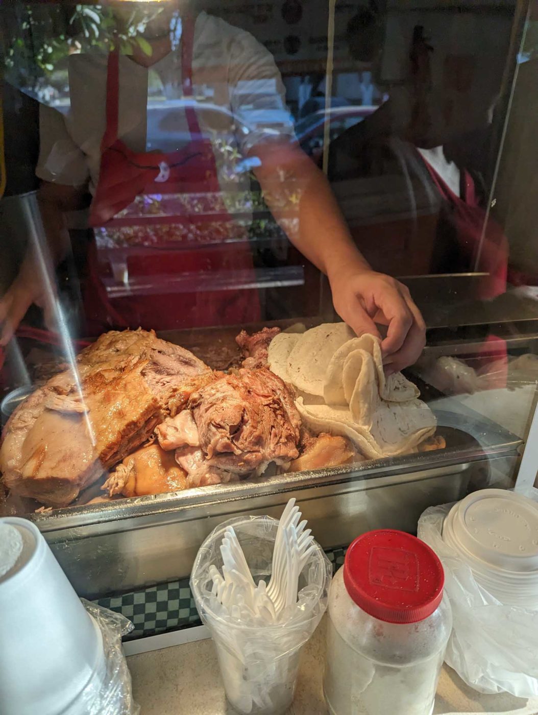 a person preparing food behind a glass counter.