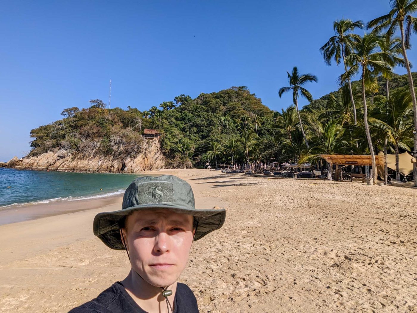 a man wearing a hat standing on a beach.