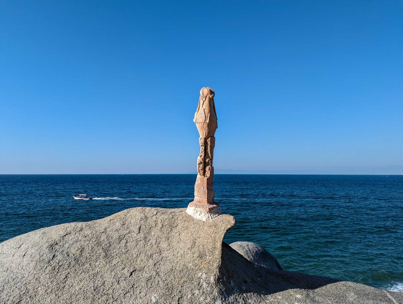 a statue on top of a large rock near the ocean.