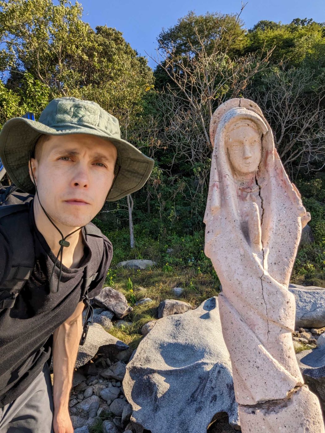 a young boy standing next to a statue of a woman.