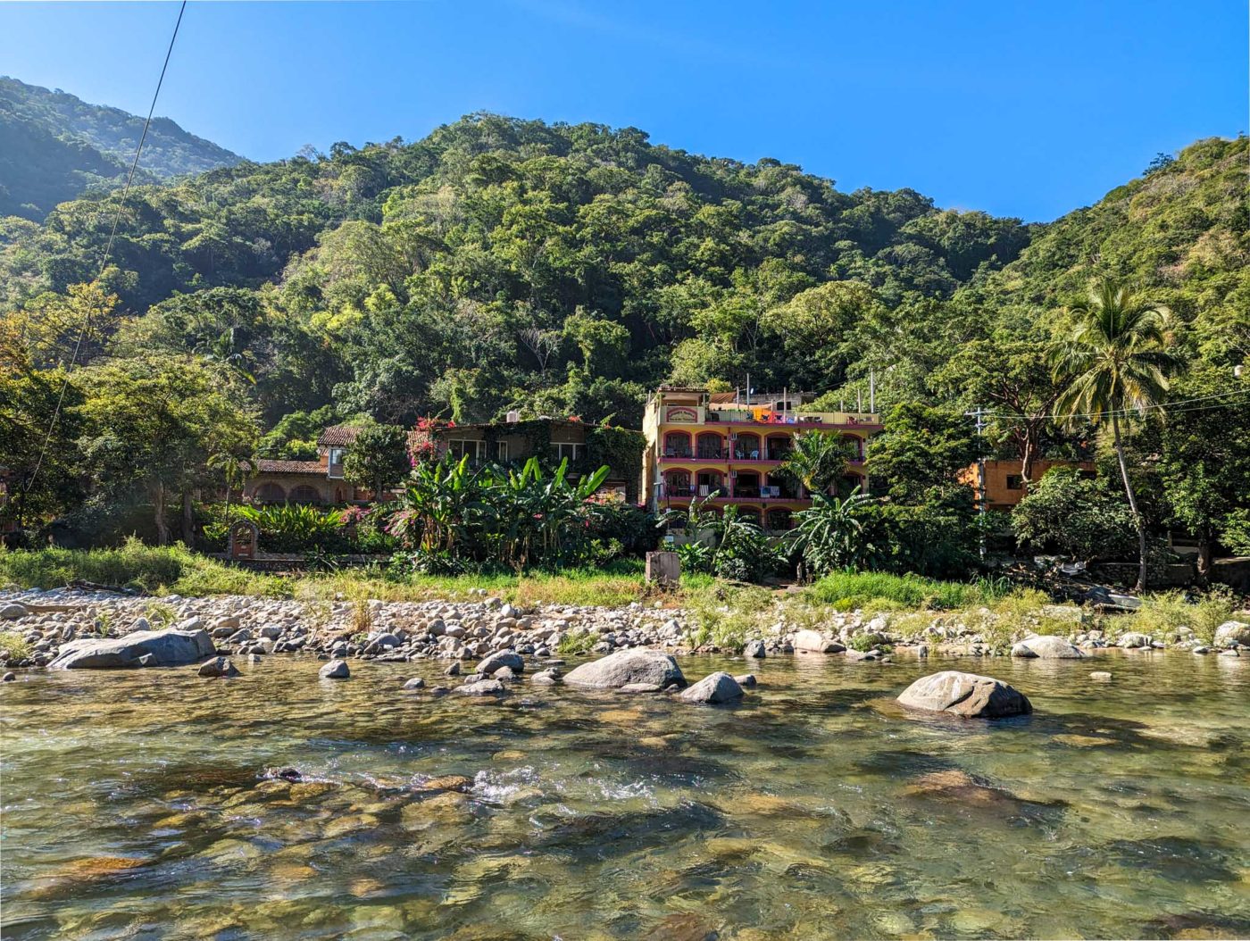 a house on the side of a river surrounded by trees.