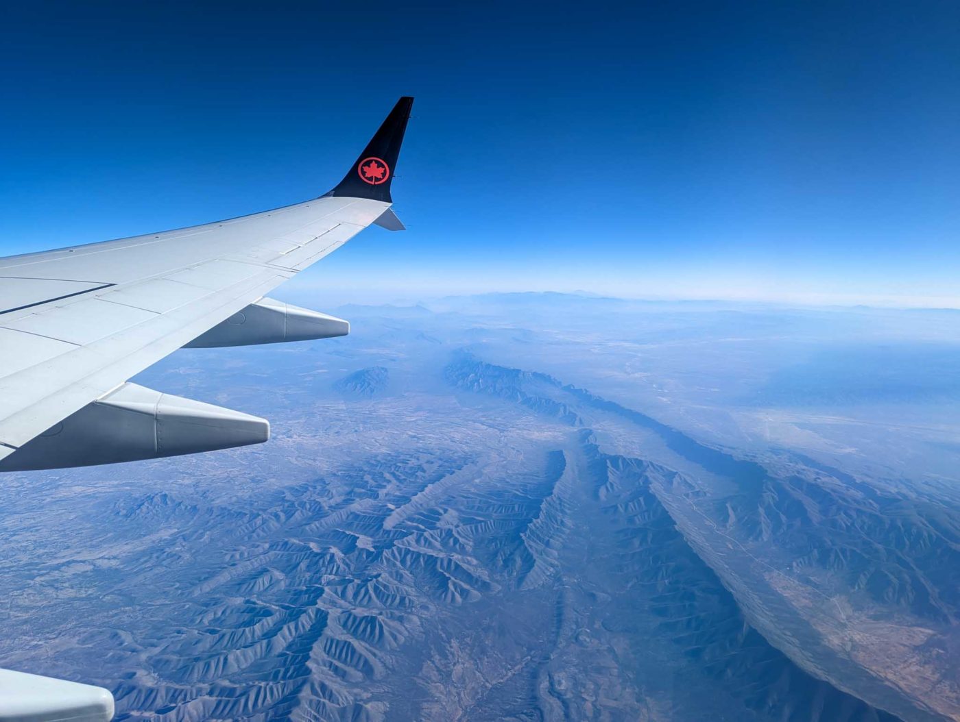 the wing of an airplane flying over a mountain range.