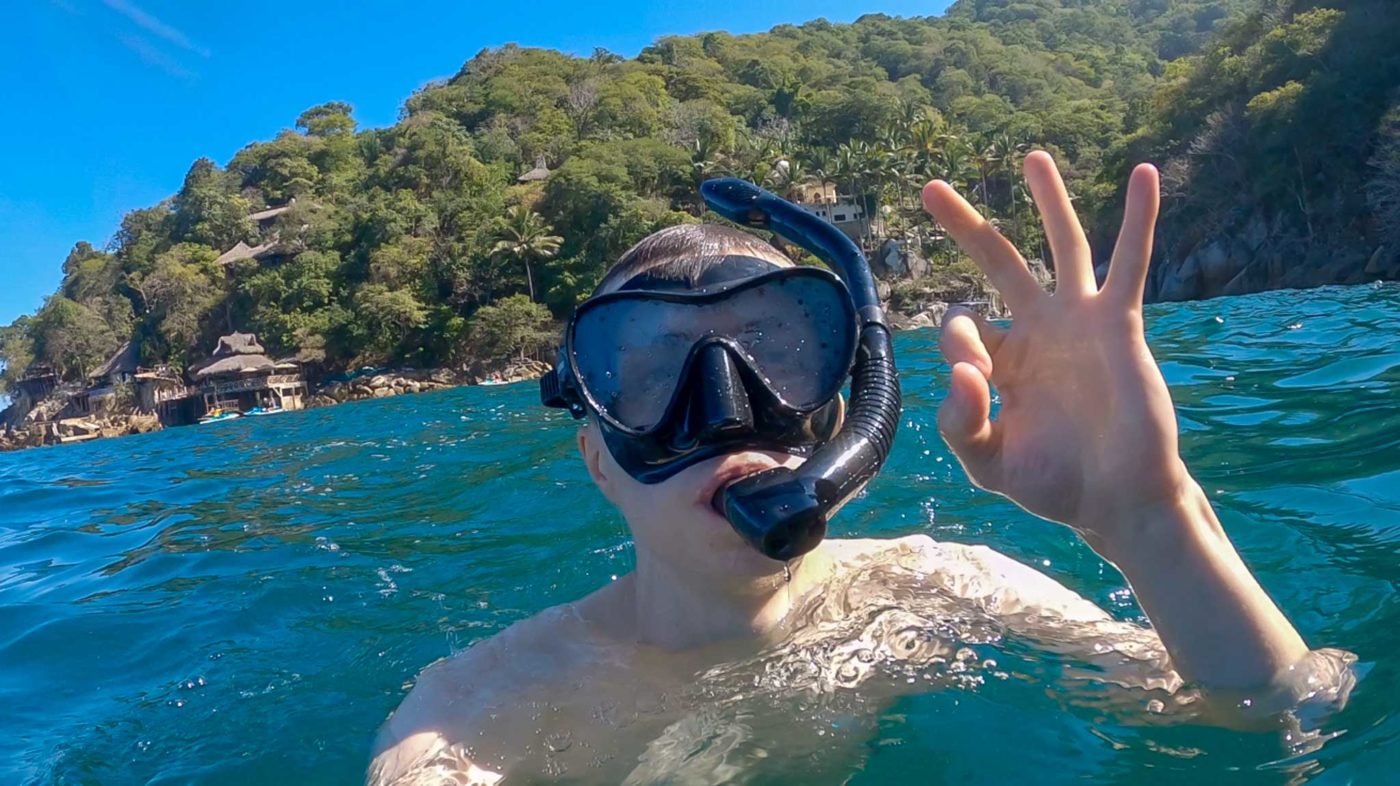 a man swimming in the ocean with a mask on his face.